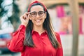 Young hispanic woman smiling happy touching his glasses at the city