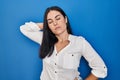 Young hispanic woman standing over blue background suffering of neck ache injury, touching neck with hand, muscular pain Royalty Free Stock Photo