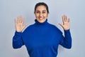 Young hispanic woman standing over isolated background showing and pointing up with fingers number ten while smiling confident and Royalty Free Stock Photo