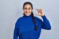 Young hispanic woman standing over isolated background smiling and confident gesturing with hand doing small size sign with Royalty Free Stock Photo