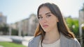 Young hispanic woman standing with serious expression looking at the camera at park