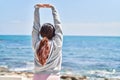 Young hispanic woman stretching arms standing on back view at seaside Royalty Free Stock Photo