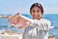 Young hispanic woman stretching arms training at seaside Royalty Free Stock Photo