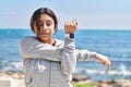 Young hispanic woman stretching arms training at seaside Royalty Free Stock Photo