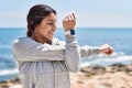 Young hispanic woman stretching arms training at seaside Royalty Free Stock Photo