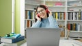 Young hispanic woman student using laptop wearing headphones at library university Royalty Free Stock Photo