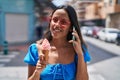 Young hispanic woman talking on smartphone eating ice cream at street Royalty Free Stock Photo