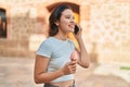 Young hispanic woman talking on the smartphone eating ice cream at street Royalty Free Stock Photo