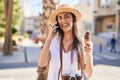Young hispanic woman tourist talking on the smartphone eating ice cream at street Royalty Free Stock Photo