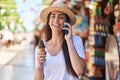 Young hispanic woman tourist talking on the smartphone eating ice cream at street market Royalty Free Stock Photo