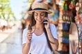 Young hispanic woman tourist talking on the smartphone eating ice cream at street market Royalty Free Stock Photo