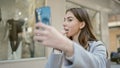 Young hispanic woman using smartphone as a mirror applying lipstick at street Royalty Free Stock Photo