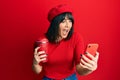 Young hispanic woman using smartphone and drinking a cup of coffee celebrating crazy and amazed for success with open eyes Royalty Free Stock Photo