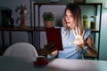 Young hispanic woman using touchpad sitting on the table at night doing stop gesture with hands palms, angry and frustration Royalty Free Stock Photo