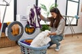 Young hispanic woman washing clothes listening to music at laundry room Royalty Free Stock Photo