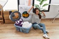 Young hispanic woman washing clothes listening to music at laundry room Royalty Free Stock Photo