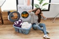 Young hispanic woman washing clothes listening to music at laundry room Royalty Free Stock Photo