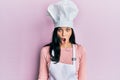 Young hispanic woman wearing baker uniform and cook hat scared and amazed with open mouth for surprise, disbelief face