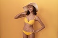 Young hispanic woman wearing bikini and summer hat smiling doing phone gesture with hand and fingers like talking on the telephone Royalty Free Stock Photo