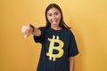 Young hispanic woman wearing bitcoin t shirt pointing to you and the camera with fingers, smiling positive and cheerful Royalty Free Stock Photo