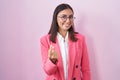 Young hispanic woman wearing business clothes and glasses beckoning come here gesture with hand inviting welcoming happy and Royalty Free Stock Photo