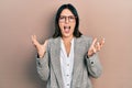 Young hispanic woman wearing business clothes and glasses crazy and mad shouting and yelling with aggressive expression and arms Royalty Free Stock Photo