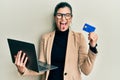 Young hispanic woman wearing business style holding laptop and credit card sticking tongue out happy with funny expression Royalty Free Stock Photo