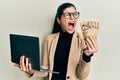 Young hispanic woman wearing business style holding laptop and hungarian forint angry and mad screaming frustrated and furious, Royalty Free Stock Photo