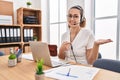 Young hispanic woman wearing call center agent headset at the office amazed and smiling to the camera while presenting with hand Royalty Free Stock Photo