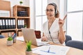 Young hispanic woman wearing call center agent headset at the office smiling happy pointing with hand and finger to the side Royalty Free Stock Photo