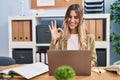 Young hispanic woman wearing call center agent headset working at the office doing ok sign with fingers, smiling friendly Royalty Free Stock Photo