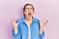 Young hispanic woman wearing casual clothes and glasses crazy and mad shouting and yelling with aggressive expression and arms Royalty Free Stock Photo
