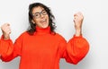 Young hispanic woman wearing casual clothes and glasses screaming proud, celebrating victory and success very excited with raised Royalty Free Stock Photo