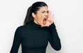 Young hispanic woman wearing casual clothes shouting and screaming loud to side with hand on mouth