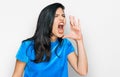 Young hispanic woman wearing casual clothes shouting and screaming loud to side with hand on mouth