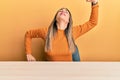 Young hispanic woman wearing casual clothes sitting on the table stretching back, tired and relaxed, sleepy and yawning for early Royalty Free Stock Photo