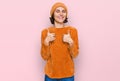 Young hispanic woman wearing casual clothes and wool cap success sign doing positive gesture with hand, thumbs up smiling and Royalty Free Stock Photo