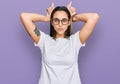 Young hispanic woman wearing casual white t shirt doing funny gesture with finger over head as bull horns Royalty Free Stock Photo