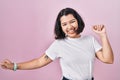 Young hispanic woman wearing casual white t shirt over pink background dancing happy and cheerful, smiling moving casual and Royalty Free Stock Photo