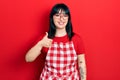 Young hispanic woman wearing cook apron and glasses doing happy thumbs up gesture with hand Royalty Free Stock Photo