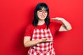 Young hispanic woman wearing cook apron and glasses gesturing with hands showing big and large size sign, measure symbol Royalty Free Stock Photo