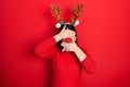 Young hispanic woman wearing deer christmas hat and red nose covering eyes and mouth with hands, surprised and shocked Royalty Free Stock Photo
