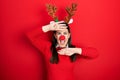 Young hispanic woman wearing deer christmas hat and red nose smiling cheerful playing peek a boo with hands showing face Royalty Free Stock Photo