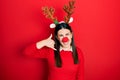 Young hispanic woman wearing deer christmas hat and red nose smiling doing phone gesture with hand and fingers like talking on the Royalty Free Stock Photo