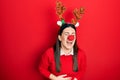 Young hispanic woman wearing deer christmas hat and red nose smiling and laughing hard out loud because funny crazy joke with