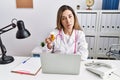 Young hispanic woman wearing doctor uniform holding pills at the clinic looking sleepy and tired, exhausted for fatigue and Royalty Free Stock Photo