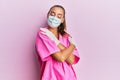 Young hispanic woman wearing doctor uniform and medical mask hugging oneself happy and positive, smiling confident Royalty Free Stock Photo