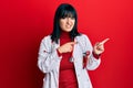 Young hispanic woman wearing doctor uniform and stethoscope pointing aside worried and nervous with both hands, concerned and Royalty Free Stock Photo