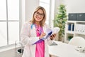 Young hispanic woman wearing doctor uniform writing on clipboard al clinic Royalty Free Stock Photo