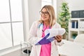 Young hispanic woman wearing doctor uniform writing on clipboard al clinic Royalty Free Stock Photo